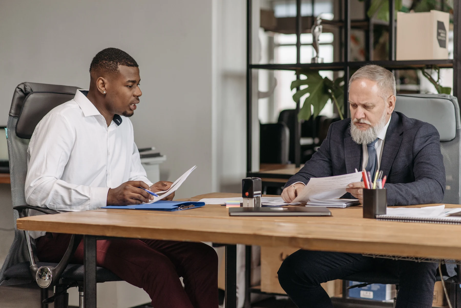 Two people discuss documents across an office table.